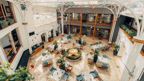A spacious indoor atrium with multiple dining areas, a central decorative garden, and a high ceiling with natural light. - Hotel Mama Cuchara by Art Hotels Ecuador (Quito)
