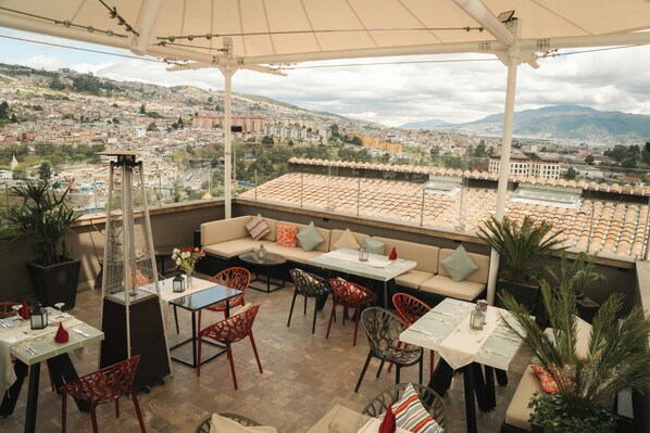 Terraza en la azotea con asientos al aire libre, un calentador y vistas de un paisaje urbano.