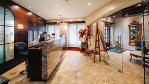 A hotel lobby with a reception desk, a large window with a view, a chandelier, and a mirror with an ornate frame. - Hotel Mama Cuchara by Art Hotels Ecuador (Quito)