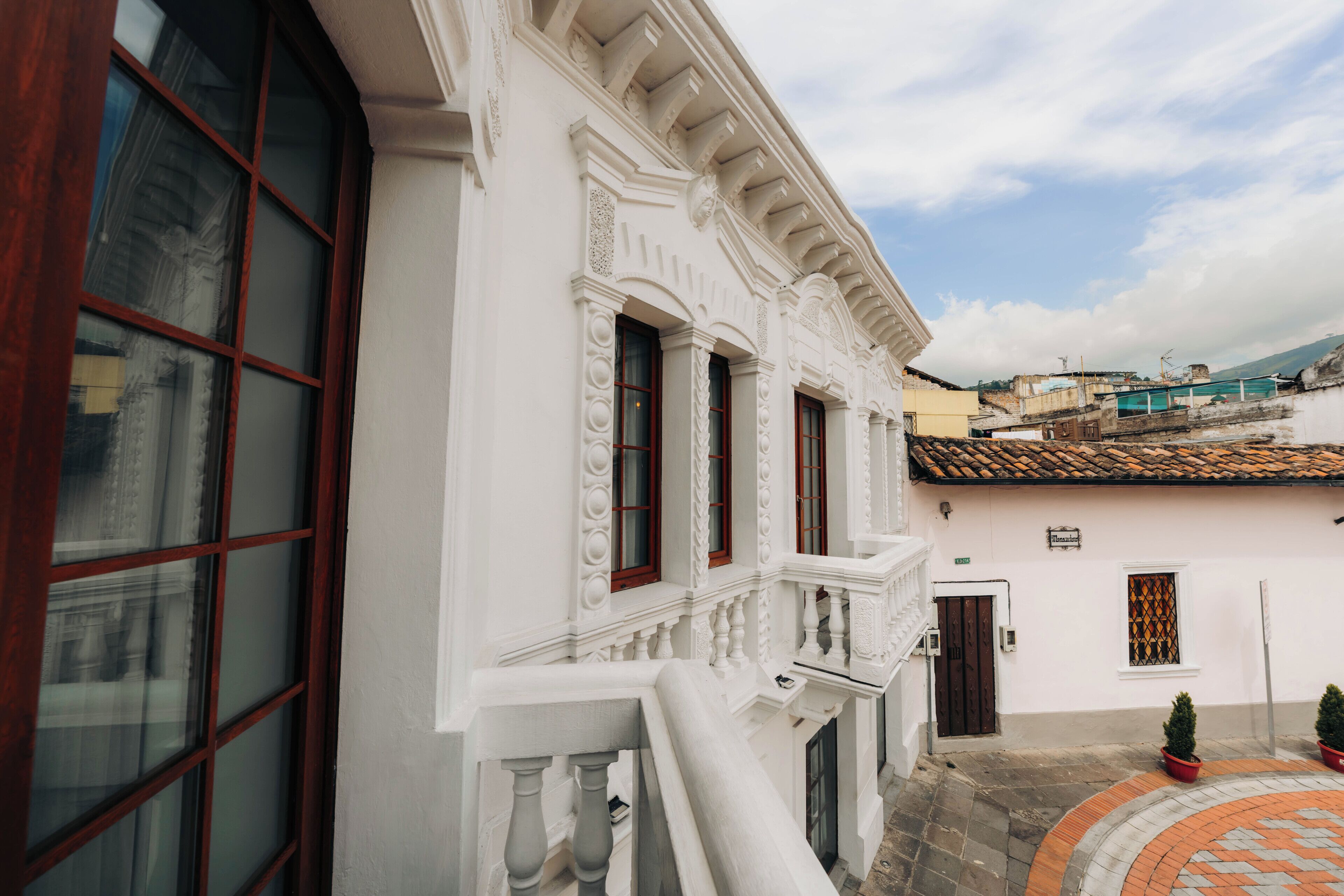 Un bâtiment blanc doté d’un balcon, d’une porte et d’une fenêtre ornée d’un motif décoratif.
