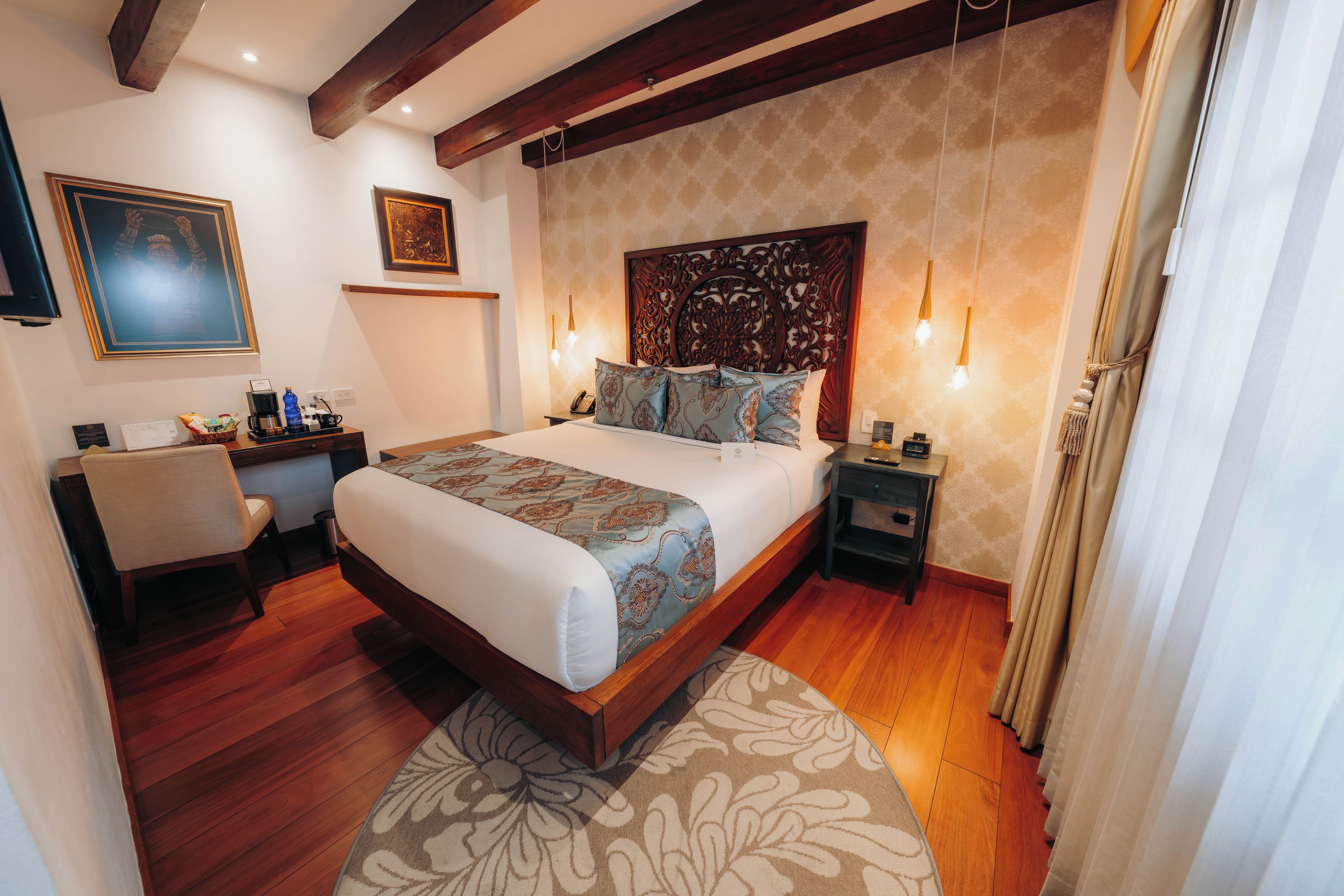 Habitación de hotel con una cama grande, un escritorio, una silla y un cabecero decorativo.
