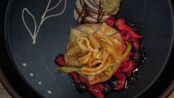 Un piattino con un dolce, frutti di bosco e un filo di cioccolato.