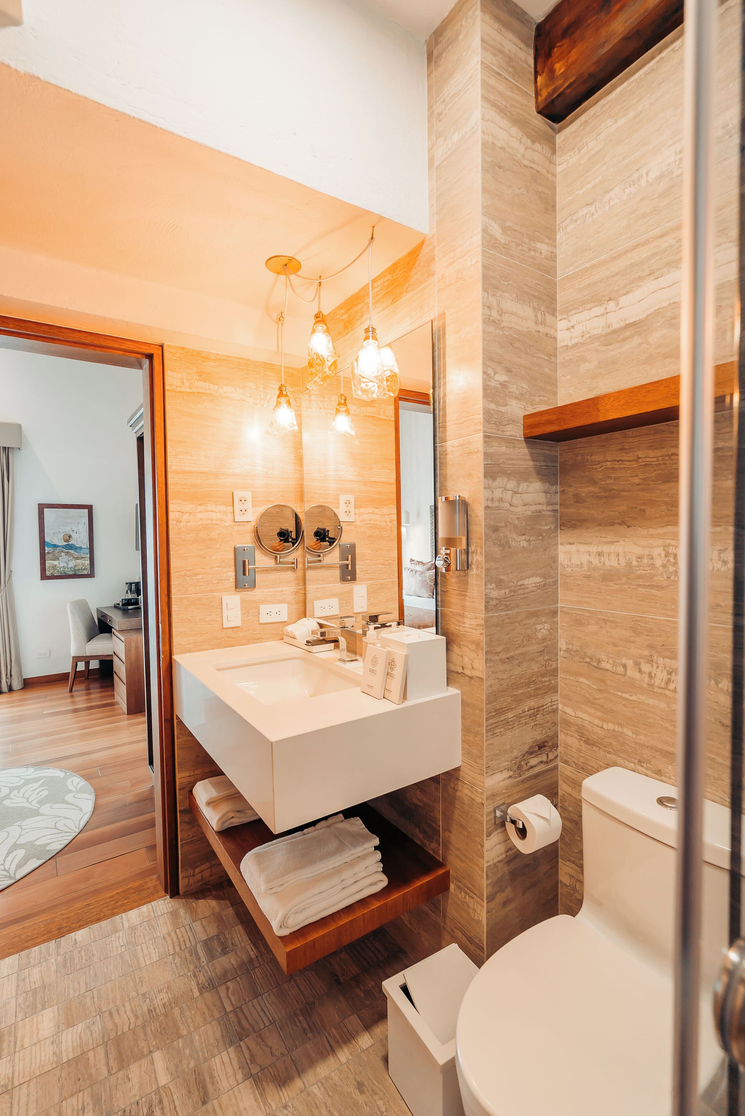 Un baño moderno con tocador de madera, un espejo grande y un inodoro.