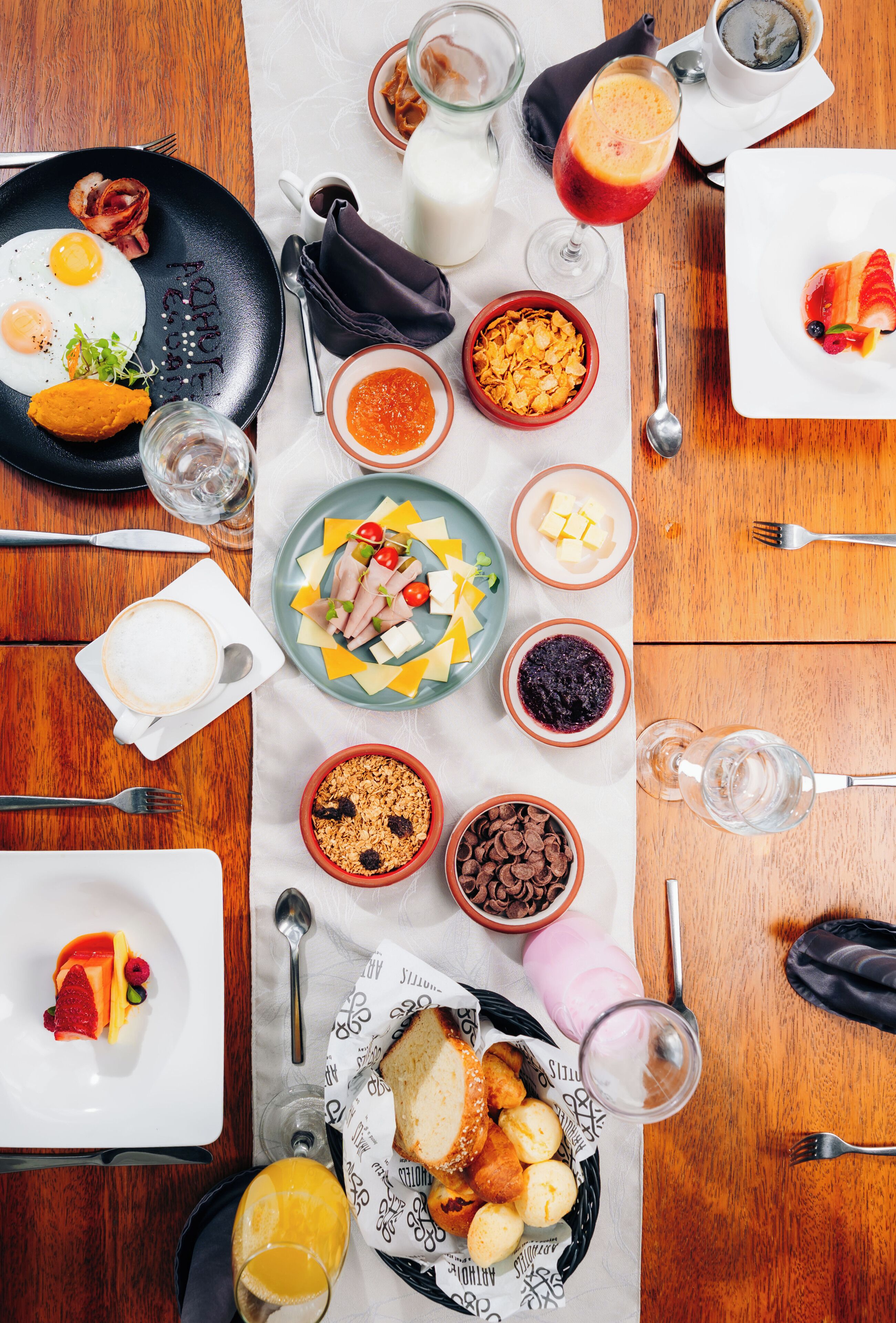 A breakfast setting with various dishes and drinks on a wooden table.