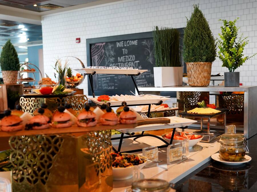 A buffet setup with various food items and decorative plants.