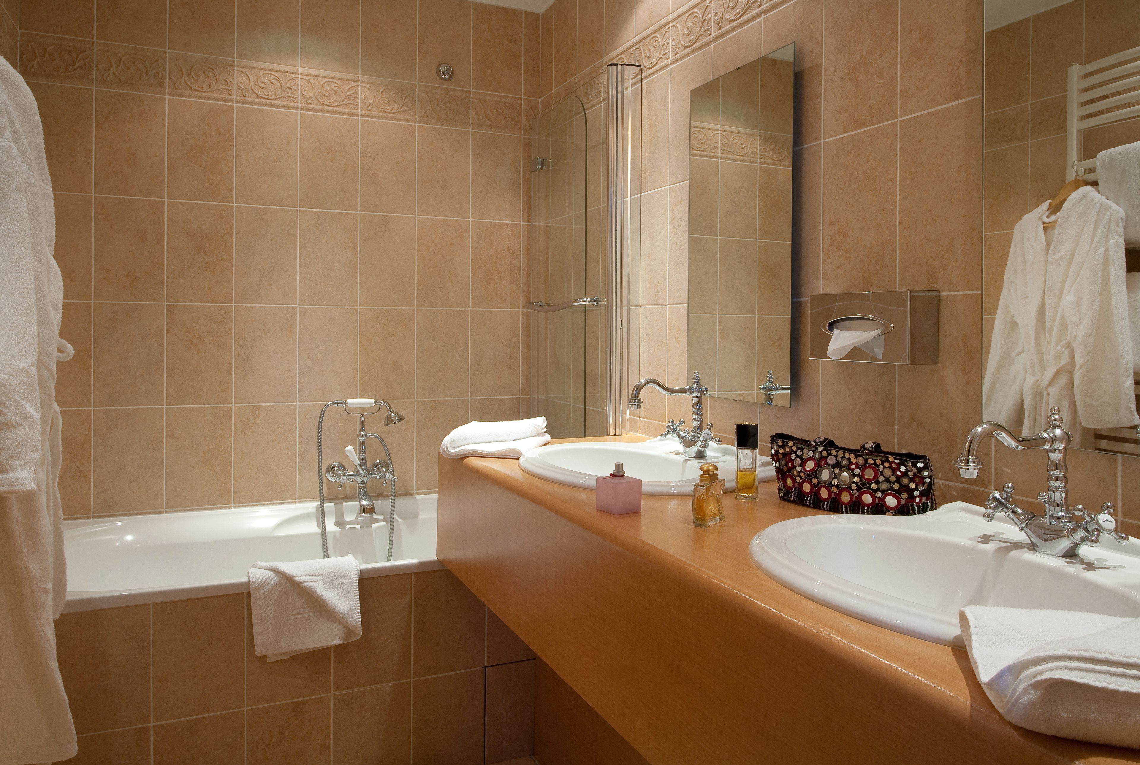 A bathroom with two sinks, a bathtub, and a large mirror.