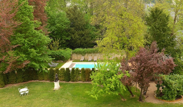 A backyard with a swimming pool, a statue, and a seating area with chairs and a table. - Le Manoir Saint Thomas (Amboise)