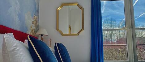 A hotel room with a bed, a large mirror, and a view of the sky through a window.