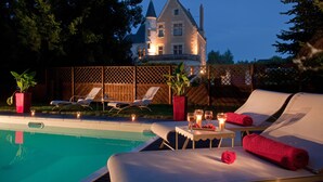 A poolside area with lounge chairs, a table with drinks, and a candle. - Le Manoir Saint Thomas (Amboise)