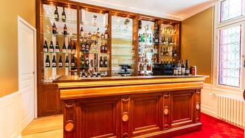 A bar area with wooden cabinetry, shelves of bottles, and glasses.