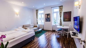A modern hotel room with a bed, sofa, dining table, chairs, and a TV. - Cosy 2 bedroom Apartment (Vienna)