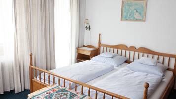 A neatly made bed with white linens, a wooden headboard, and a small bedside table with a lamp.