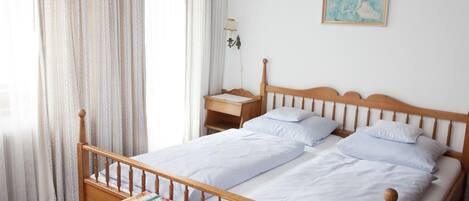 A neatly made bed with white linens, a wooden headboard, and a small bedside table with a lamp.