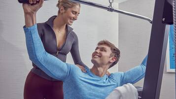 A gym with exercise equipment and a person using a cable machine.