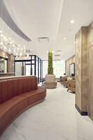A modern lobby with a curved seating area, a tall vertical garden, and a large mirror.