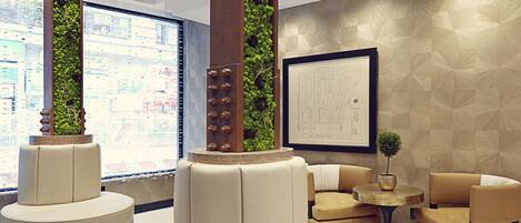 A modern lobby with circular seating, a large window, and a green vertical garden.