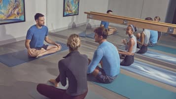 A yoga class in a room with mirrored walls and a ballet barre.