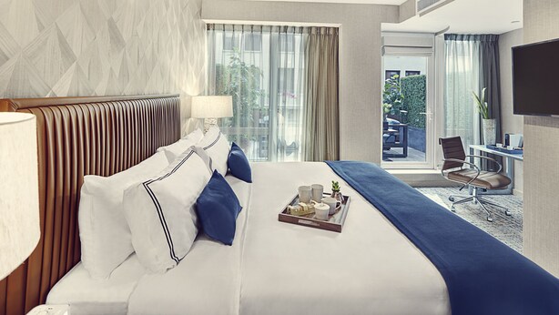 A hotel room with a large bed, a desk, and a view of the outdoors. - Artezen Hotel (New York)