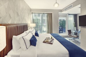 A hotel room with a large bed, a desk, and a view of the outdoors. - Artezen Hotel (New York)