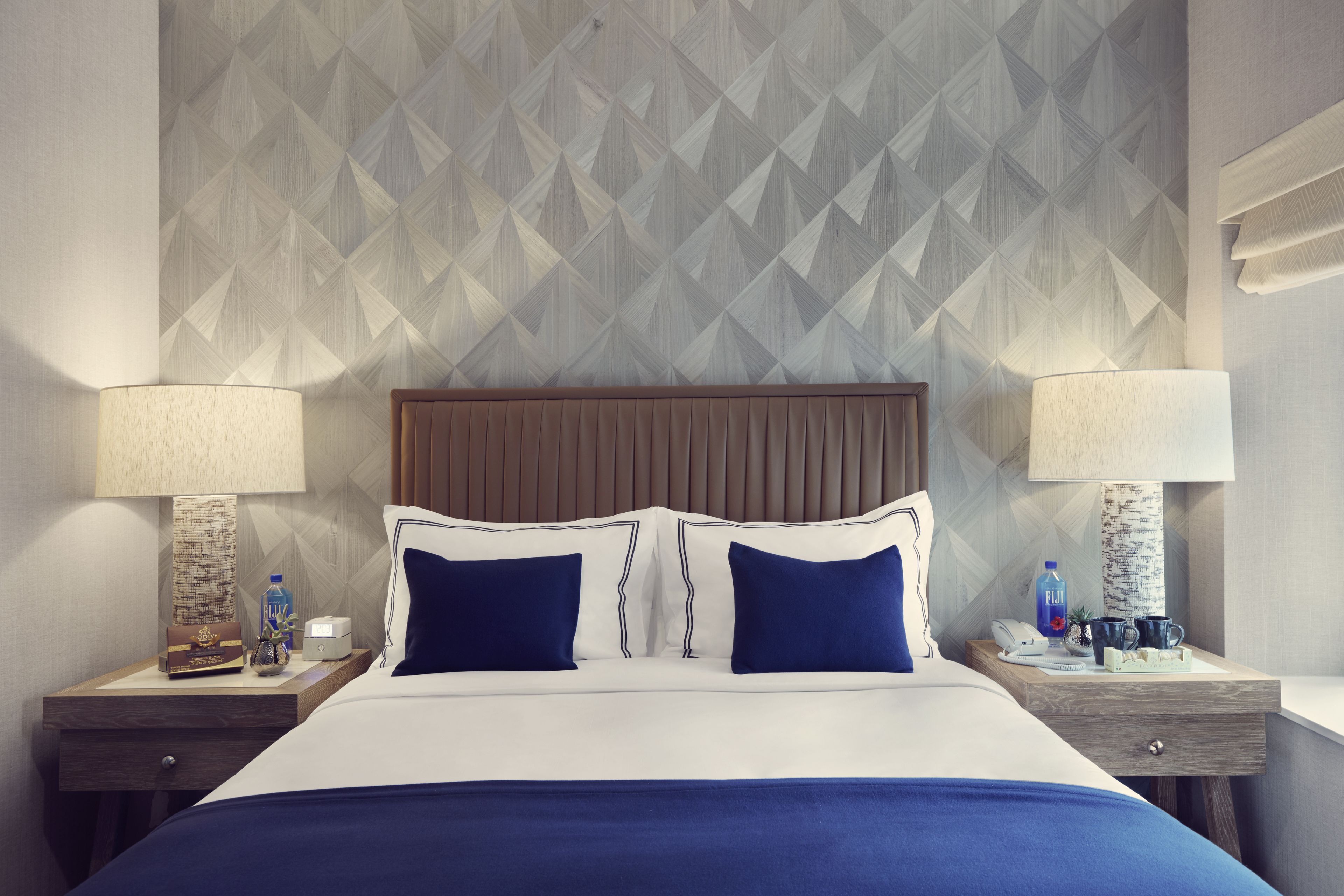 Una camera d'hotel con un letto grande, due comodini e una parete con motivo geometrico.