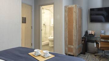 Ein Hotelzimmer mit Bett, Schreibtisch mit Stuhl, Fernseher und einem durchgegangenen Tür sichtbaren Badezimmer.