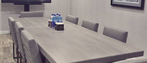 A conference room with a long table, six chairs, a flat-screen TV, and a framed map on the wall.