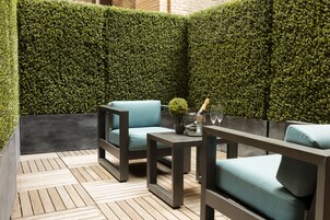 A patio area with a wooden floor, two sofas, a small table, and a potted plant.