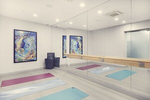 A modern fitness room with large mirrors, yoga mats, and abstract paintings on the walls.