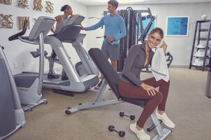 Uma academia com esteiras, aparelhos de musculação e halteres.
