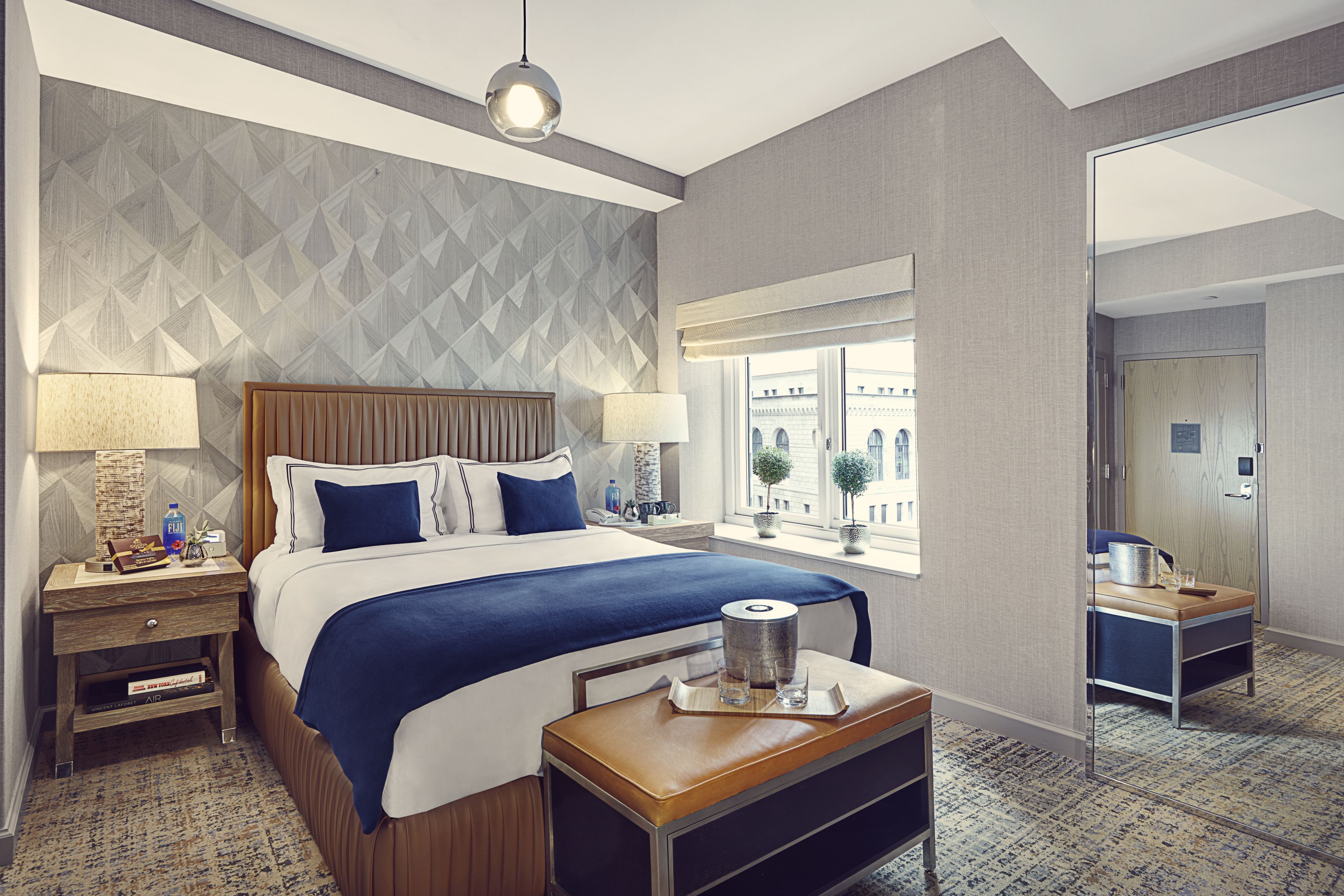 A hotel room with a large bed, two bedside tables, a nightstand, a window with a view, and a small table with a tray.