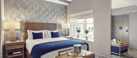 A hotel room with a large bed, two bedside tables, a nightstand, a window with a view, and a small table with a tray.