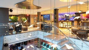 A modern hotel lobby with a glass atrium, a bar area, and seating arrangements. - Artezen Hotel (New York)
