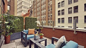 A rooftop terrace with outdoor seating, a potted plant, and a champagne bottle. - Artezen Hotel (New York)