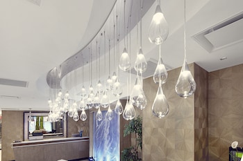 A modern hotel lobby with a glass atrium, a bar area, and seating arrangements. at Artezen Hotel
