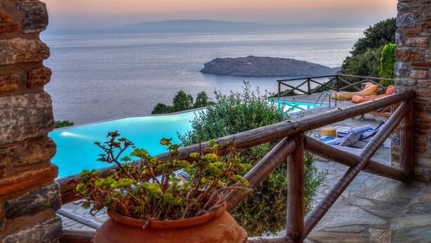A stone balcony with a view of the sea, a swimming pool, and a potted plant. - Etoile De Mer Villa (Andros)