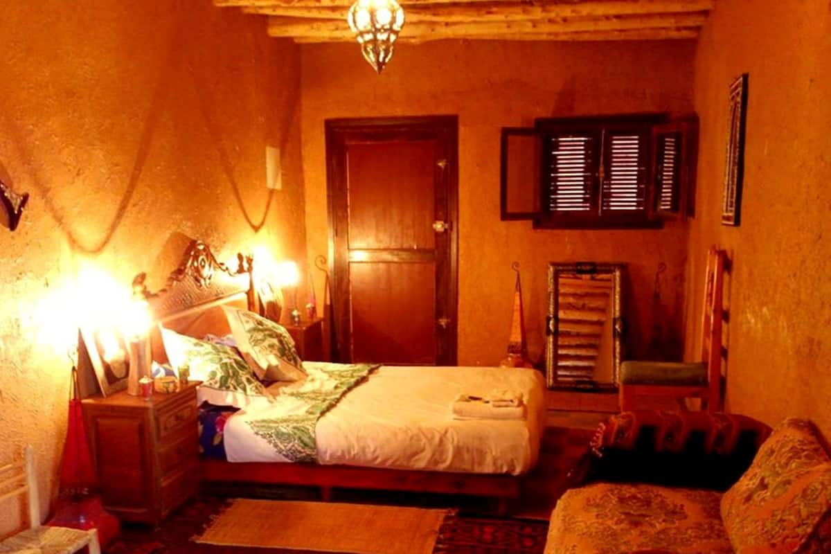 Un dormitorio acogedor con cama, una silla, un aparador y una puerta.