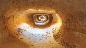 A tunnel-like structure with rough, earthy walls and a central opening. - Tarmguist (Asrir)
