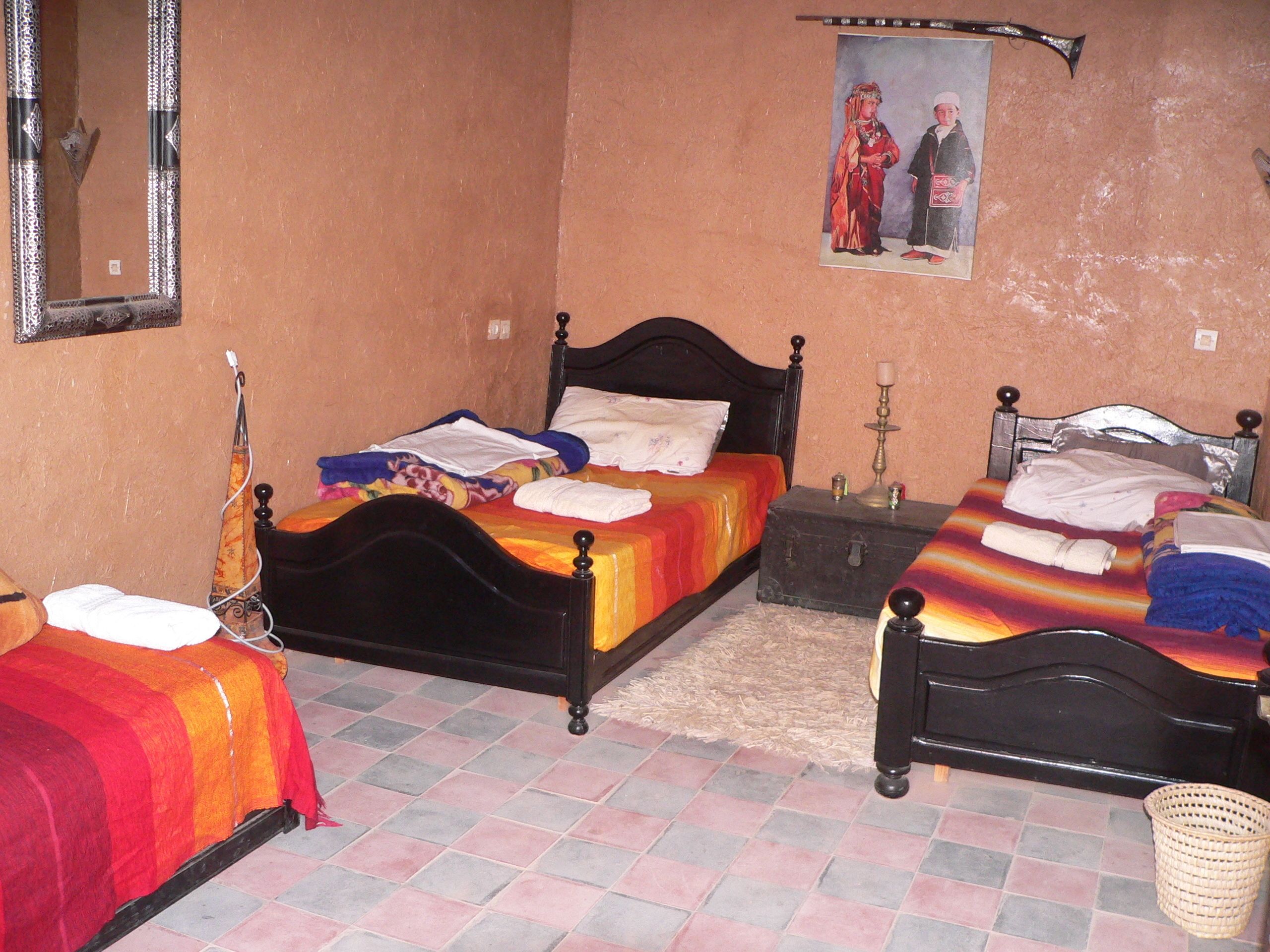 A bedroom with two beds, a mirror, a picture on the wall, and a small table with a candle.