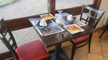 A dining table with a number 7 placemat, two plates with croissants, a coffee cup, and a sugar bowl.