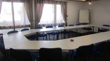 Una sala de conferencias con una larga mesa, sillas azules y una pizarra.