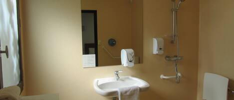 A bathroom with a sink, mirror, towel rack, shower, and toilet.