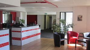 A reception area with a tiled floor, a reception desk, and seating arrangements. - Hôtel Le Saint-Joseph (Saint-Éloy-les-Mines)