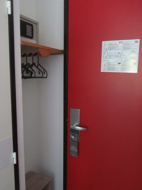 Eine rote Tür mit einer Metallklinke und einem kleinen Schild an der Wand.