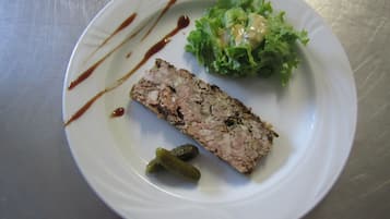 Une assiette blanche avec une tranche de viande, une portion de laitue et un cornichon.