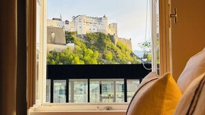 A hotel room with a large window offering a view of a castle on a hill.
