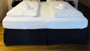 A double bed with white linens, two nightstands with lamps, and two wall-mounted paintings.