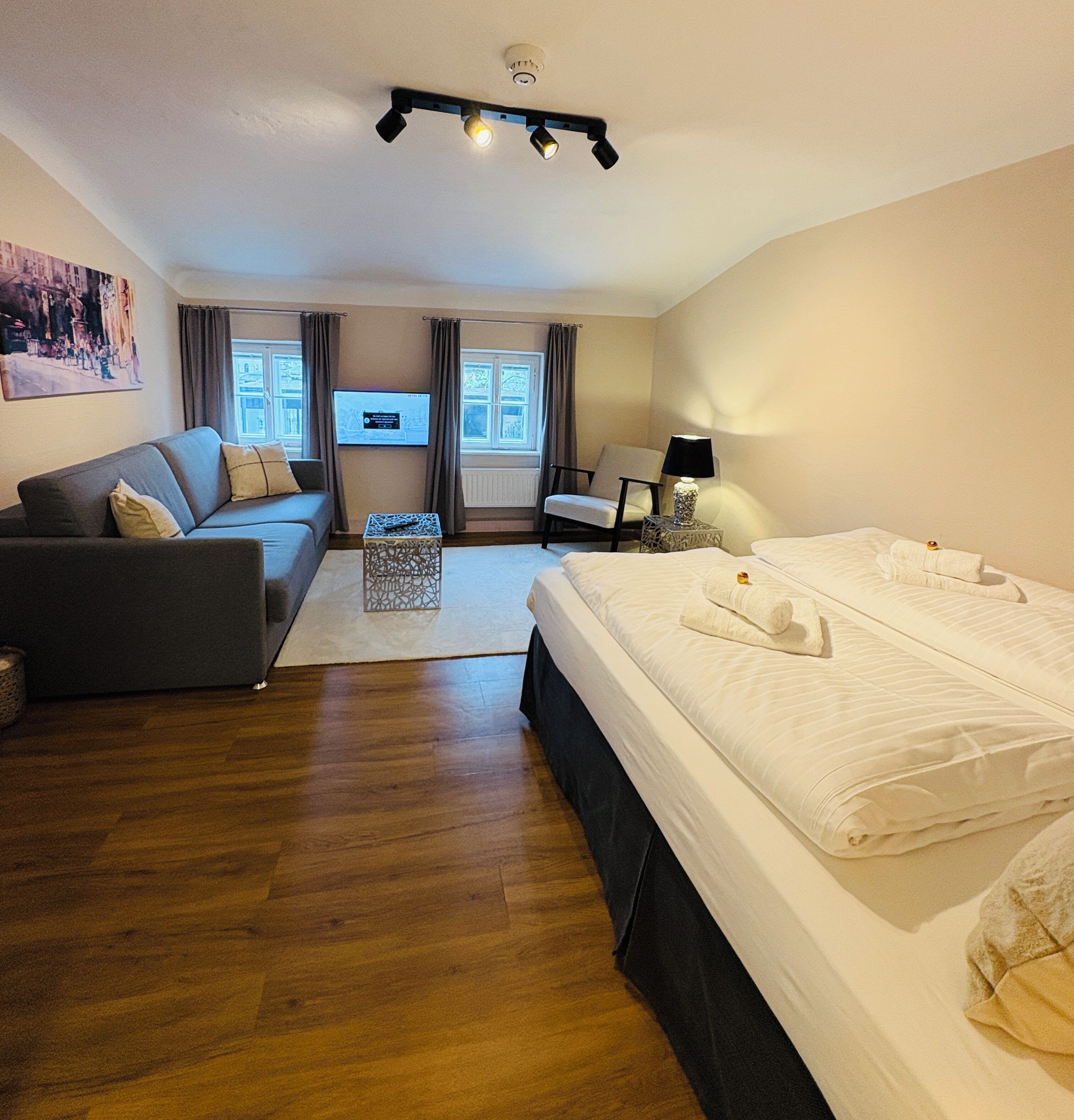 Une chambre d’hôtel avec un grand lit, un canapé, une télévision et un bureau.