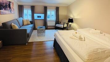 Une chambre d’hôtel avec un grand lit, un canapé, une télévision et un bureau.