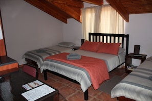 A bedroom with two beds, wooden headboards, a desk with a chair, and a small table. - Anandi Guesthouse Swakopmund (Swakopmund)