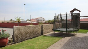 Un muro de ladrillo, un trampolín y un edificio rojo al fondo.